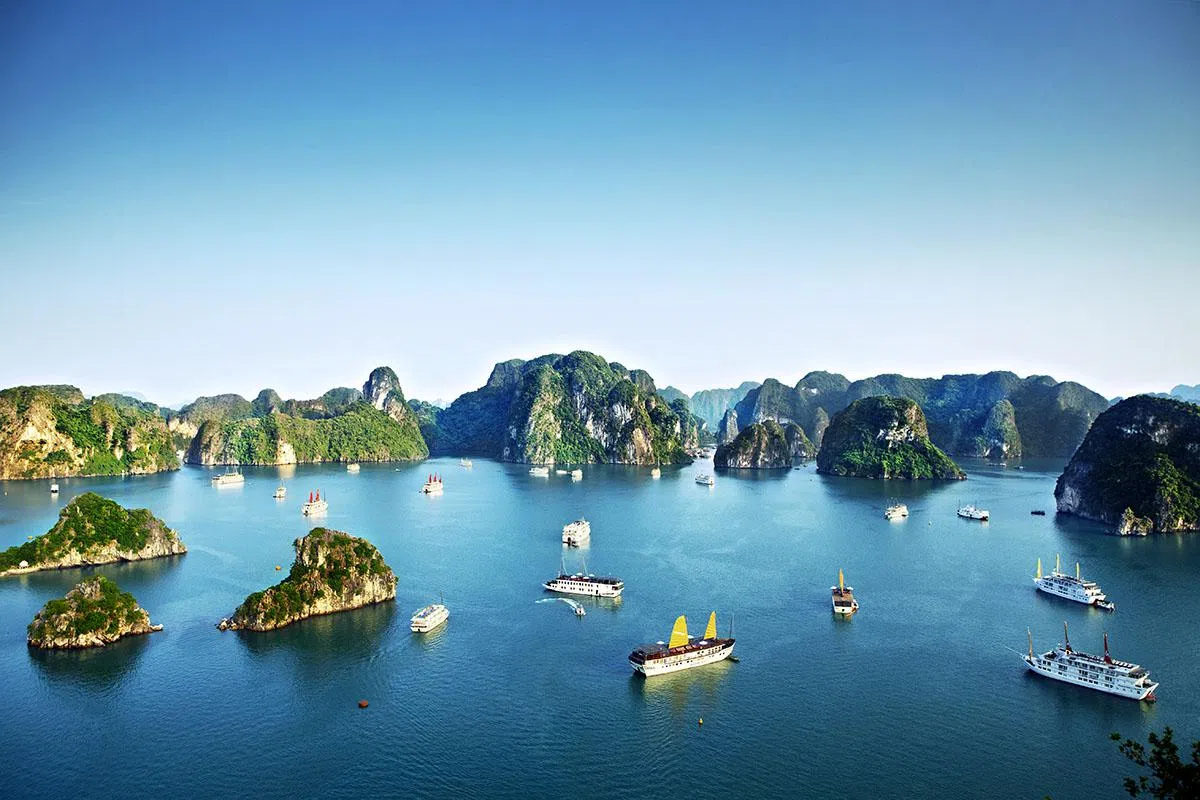 Chinese junks and cruise ships passing by limestone islands in Halong Bay.
