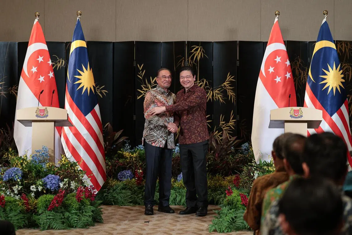 马来西亚首相安华（左）12月4日到访新加坡出席新马领导人非正式峰会，与新加坡总理黄循财（右）召开联合记者会。