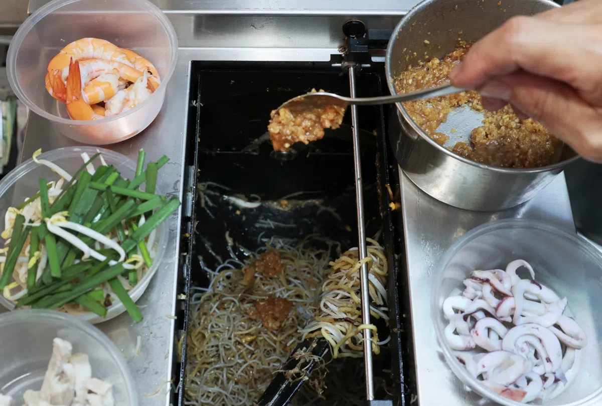 “机器人头手”仍须仰赖员工将正确比例的食材、酱料放入锅中。