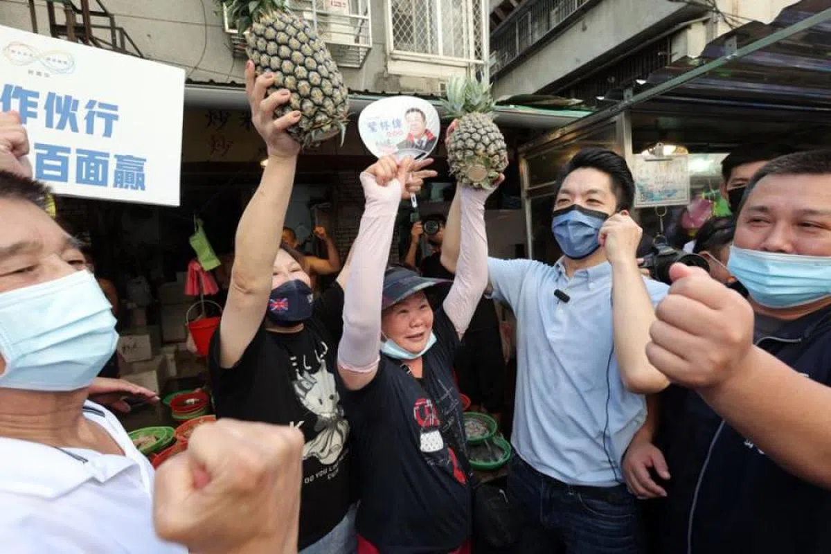 台北市长候选人蒋万安（右二）和支持者高举凤梨合影。（联合报）