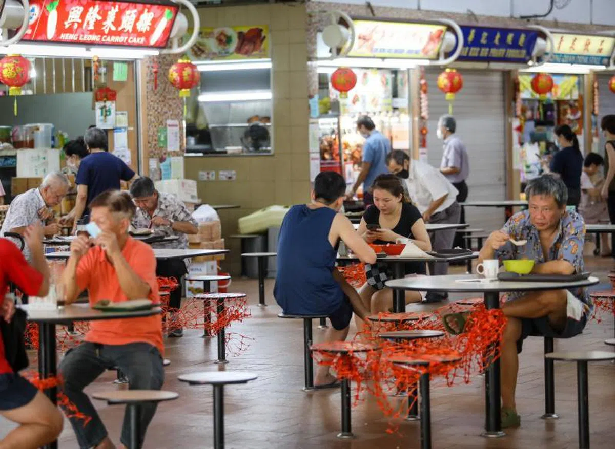  不论食客是否接种疫苗，小贩中心都只能允许两人同桌用餐。（联合早报） 