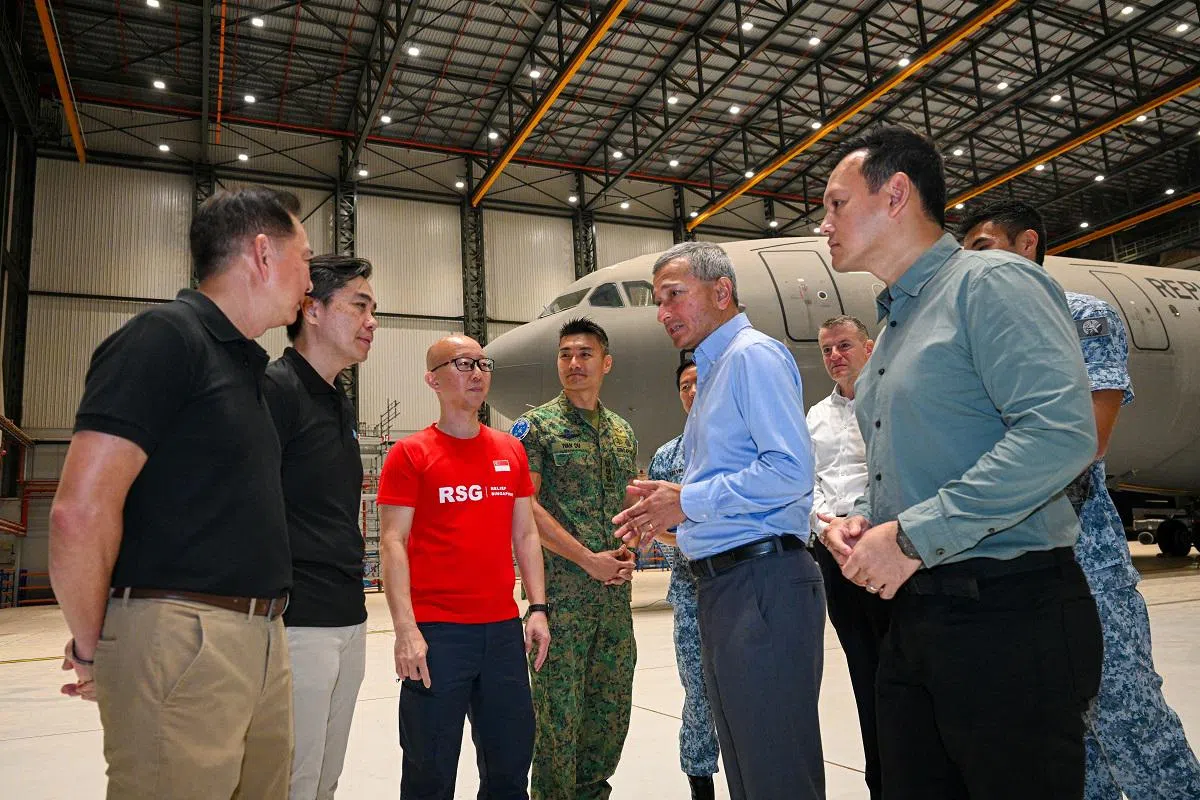 维文（着浅蓝衬衫者）为准备到约旦进行加沙人道物资输送任务的我国运输机送行。（每日新闻）