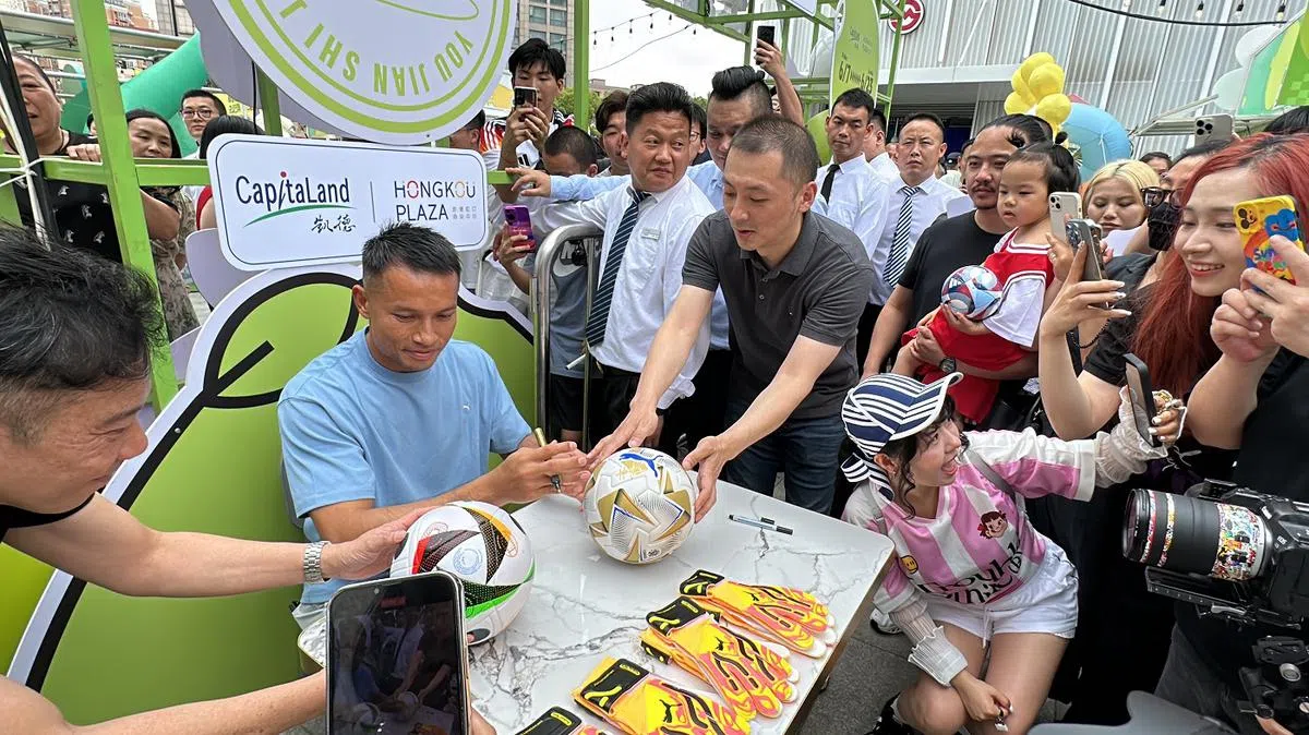 狮城门将哈山在上海出席商场活动时，受到守候在现场的大批中国民众欢迎。中国球迷拿着足球向哈山索取签名。（联合早报）