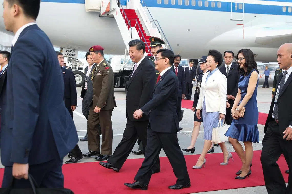 新中建交25周年，中国国家主席习近平于2015年11月6日抵达新加坡进行国事访问。习近平主席（红地毯上者左一），由新加坡财政部长王瑞杰（左二）以侍从部长的身份负责接机。习近平夫人彭丽媛（右二）则由王瑞杰夫人章慧霓（右一）陪同。（海峡时报）