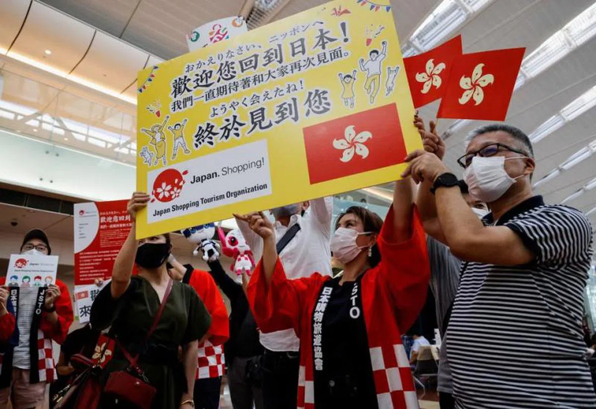 日本6月恢复允许小型团外国游客入境时，旅游业者在机场举牌欢迎香港旅客抵达。（法新社）