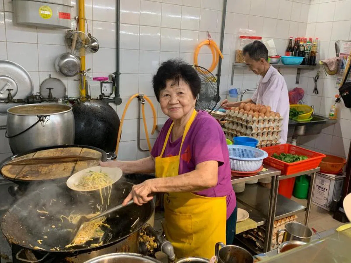  王爱莲（83岁）是本地最老的小贩之一，与二儿子黄关麟（60岁）一起经营莲香熟食。（卢凌之摄） 