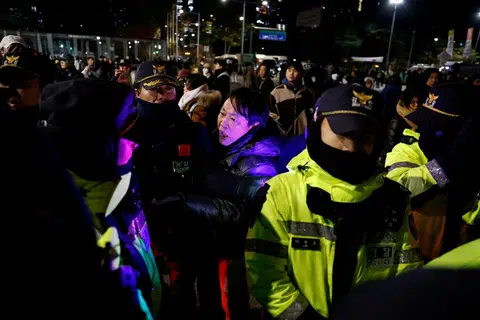 戒严令发布后当晚，一名抗议民众和封锁国会的警员对峙。（路透社）
