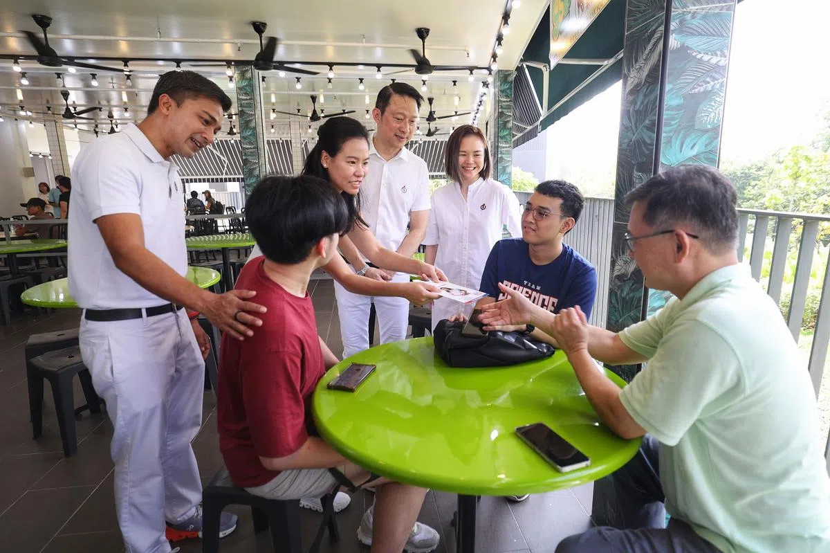 人民行动党盛港四支部主席（站立者，左起）埃尔米、王诗佳、蓝彬明、黎曦怡，一起走访盛港Rivervale Shores和万国熟食中心与居民交流。（联合早报）