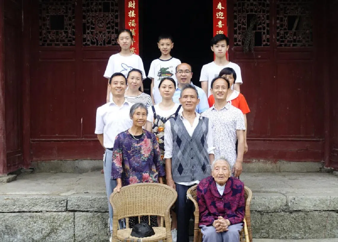 杜虎珍（前排坐者）与儿子黄发昌（第二排中）与其他家人合照。图中椅子上的帽子就是丈夫离别前留下的。（黄丽英提供）