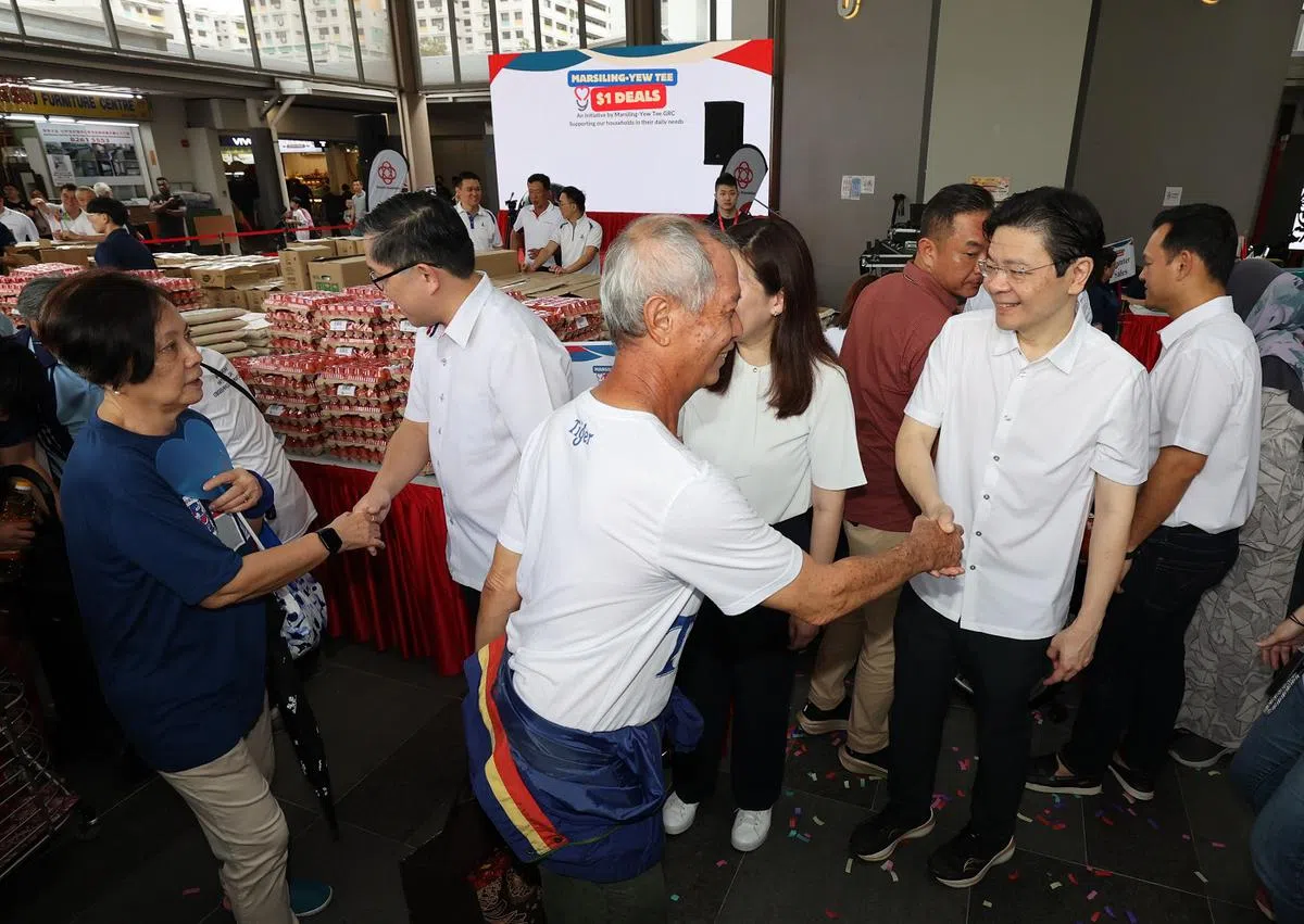总理兼财政部长黄循财（前排右一）在马西岭油池1元特价优惠计划推介仪式上，与前来兑换特价品的居民握手致意； 右二起为马西岭—油池集选区议员苏慧敏（被遮挡）、任梓铭。后排右一为同选区议员扎吉哈。（联合早报）
