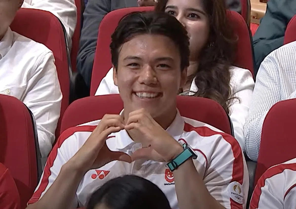 墨士廉在国庆群众大会现场，对着镜头比出爱心手势。（视频截图）