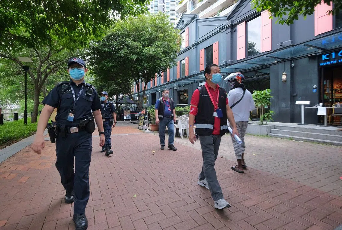 警察在新加坡河畔的罗拔申码头巡视，确保那里的民众都有遵循社交安全距离。（海峡时报）
