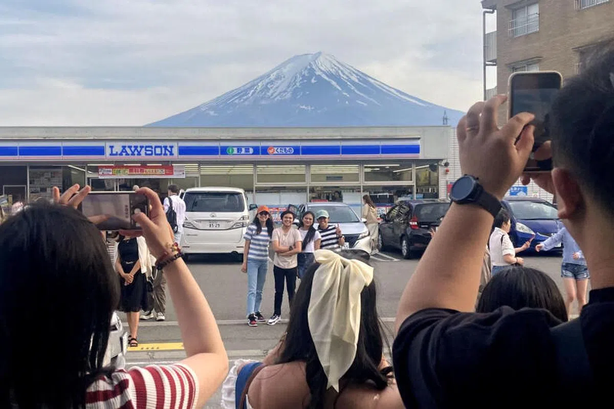 日本河口湖一家Lawson便利店，背靠壮丽的富士山，蓝白相间的招牌，与山顶的洁白雪峰相映成趣，是热门打卡景点。（路透社）