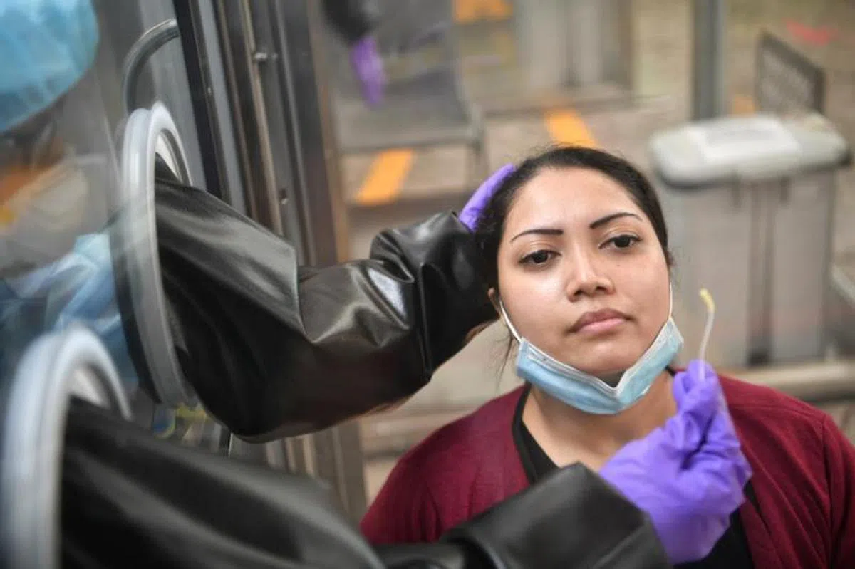  更安全的“隔离式”拭子检测。医护人员手中拿的小棉棒就是用来伸入鼻腔的拭子。（海峡时报） 