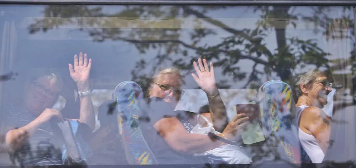  得以乘车离开的乘客都开心地向车外的媒体挥手告别。（新明日报） 