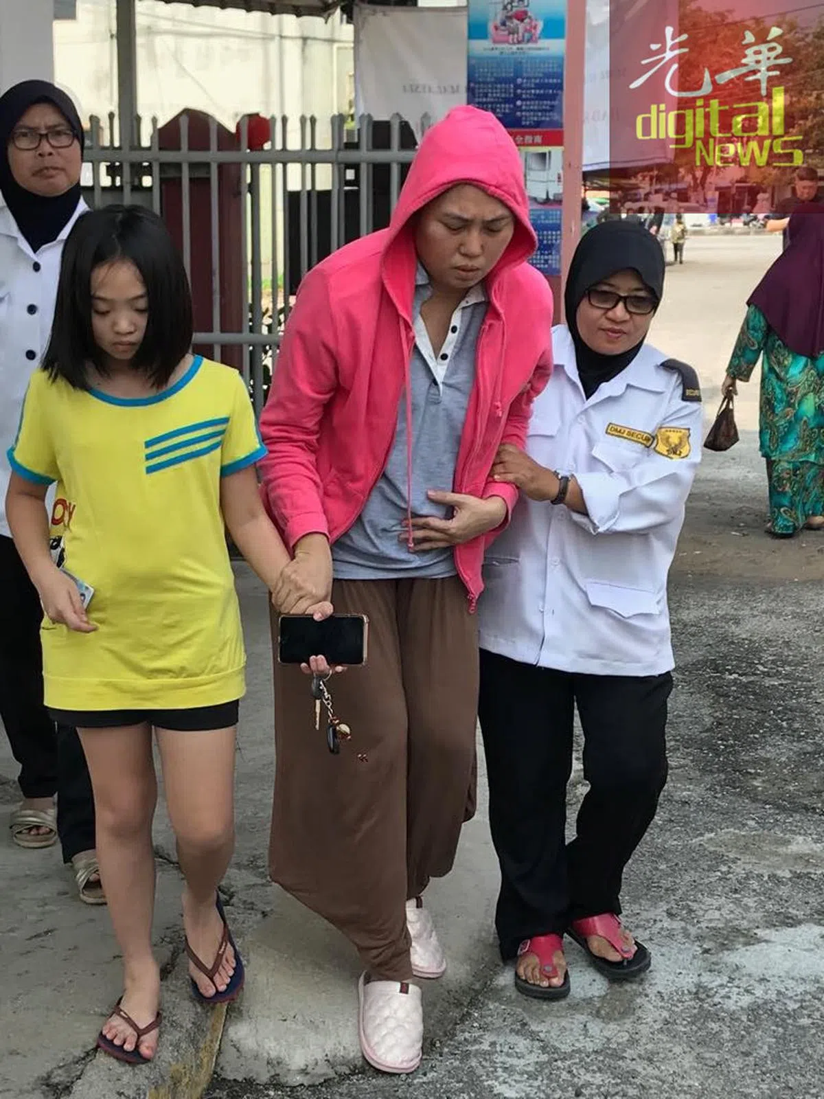  陈帼彩（中）在女儿（左）与工作人员的搀扶下，完成投票。（光华日报） 