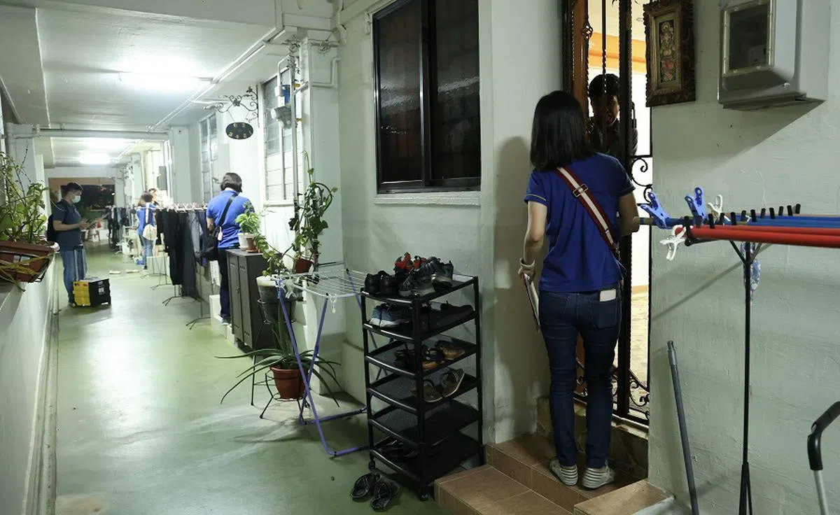 建屋发展局人员在2022年11月到宏茂桥3道第562座至565座组屋挨家逐户，向受SERS影响的居民说明实际赔偿额。（联合早报）