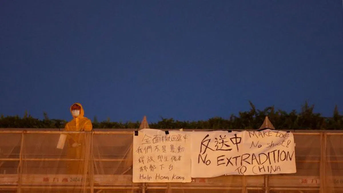  身穿黄色雨衣悬挂“反送中”横幅的香港梁姓男子疑似以死明志。（互联网） 