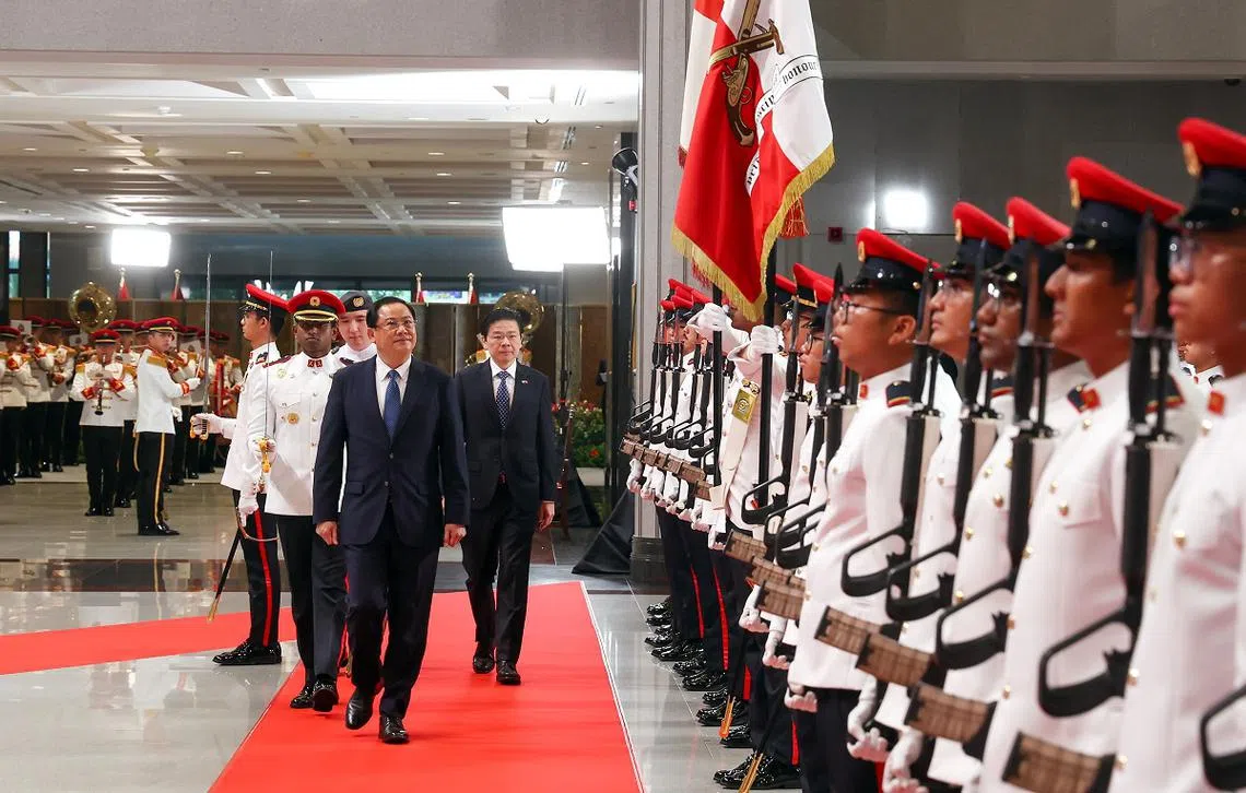 老挝总理宋赛（中）在黄循财总理的陪同下，在国会大厦检阅仪仗队。（联合早报）