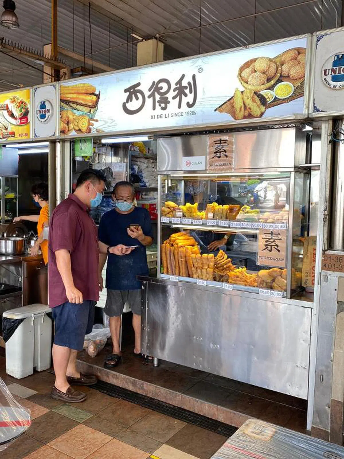  西得利董事许环杰（左）通过PayNow，向小贩摊主顾客收款。（西得利提供） 