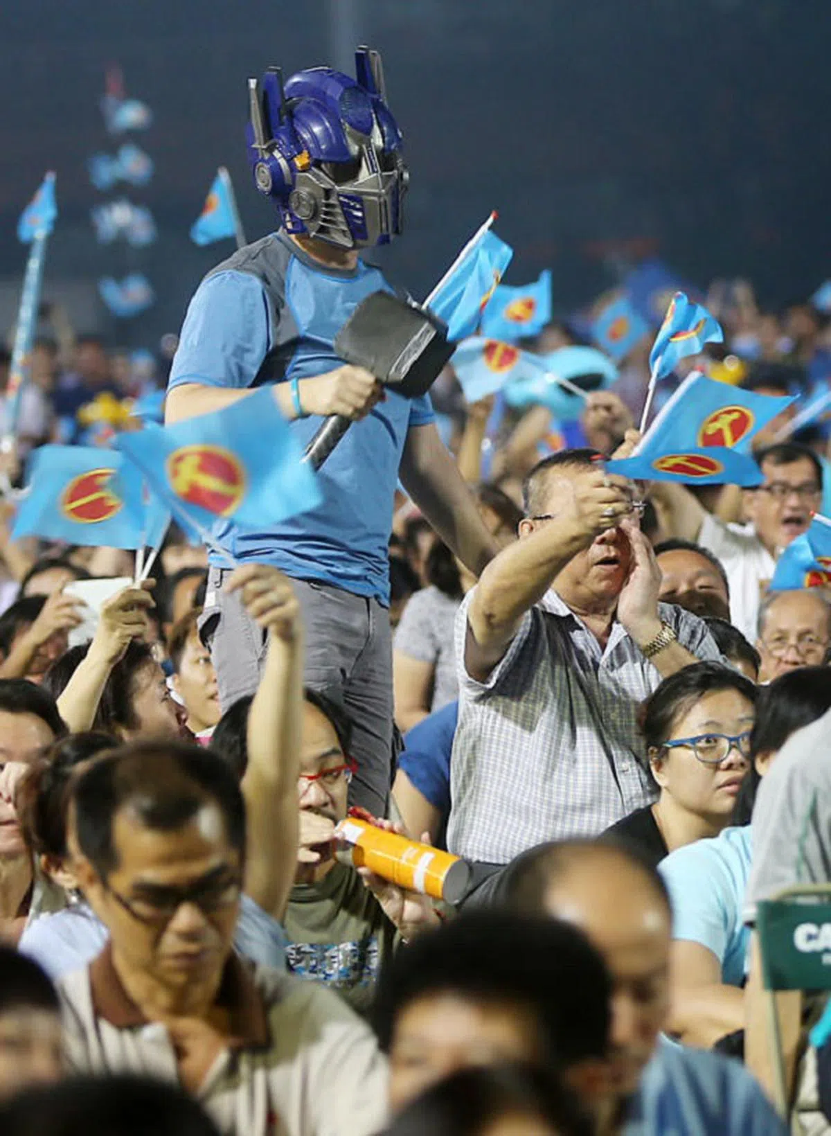  一名工人党支持者出席群众大会时戴上面具，还手持“铁锤”道具。（新明日报） 