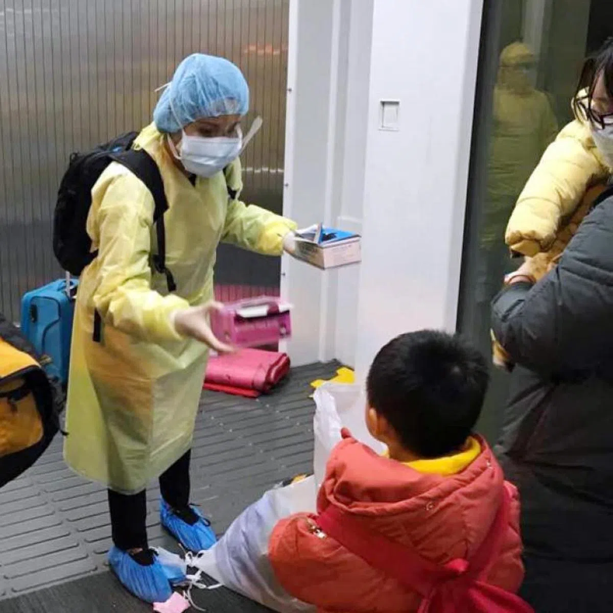  新加坡人和他们的家属上在撤离武汉上飞机前，获外交部人员分派的口罩。（外交部提供） 