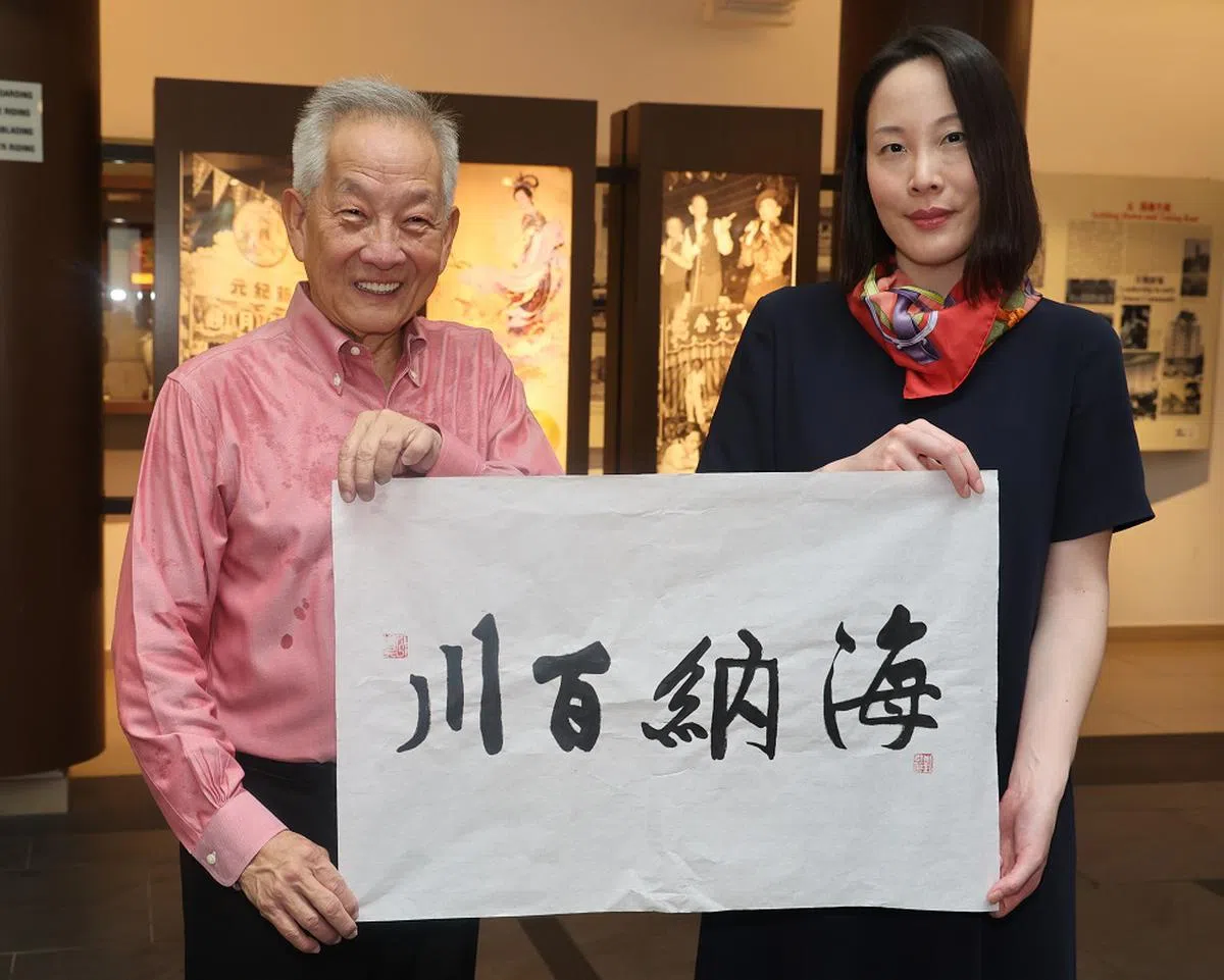 黄国松（左）把刘以真（右）的书法作品“海纳百川”送给新加坡宗乡总会。（联合早报）