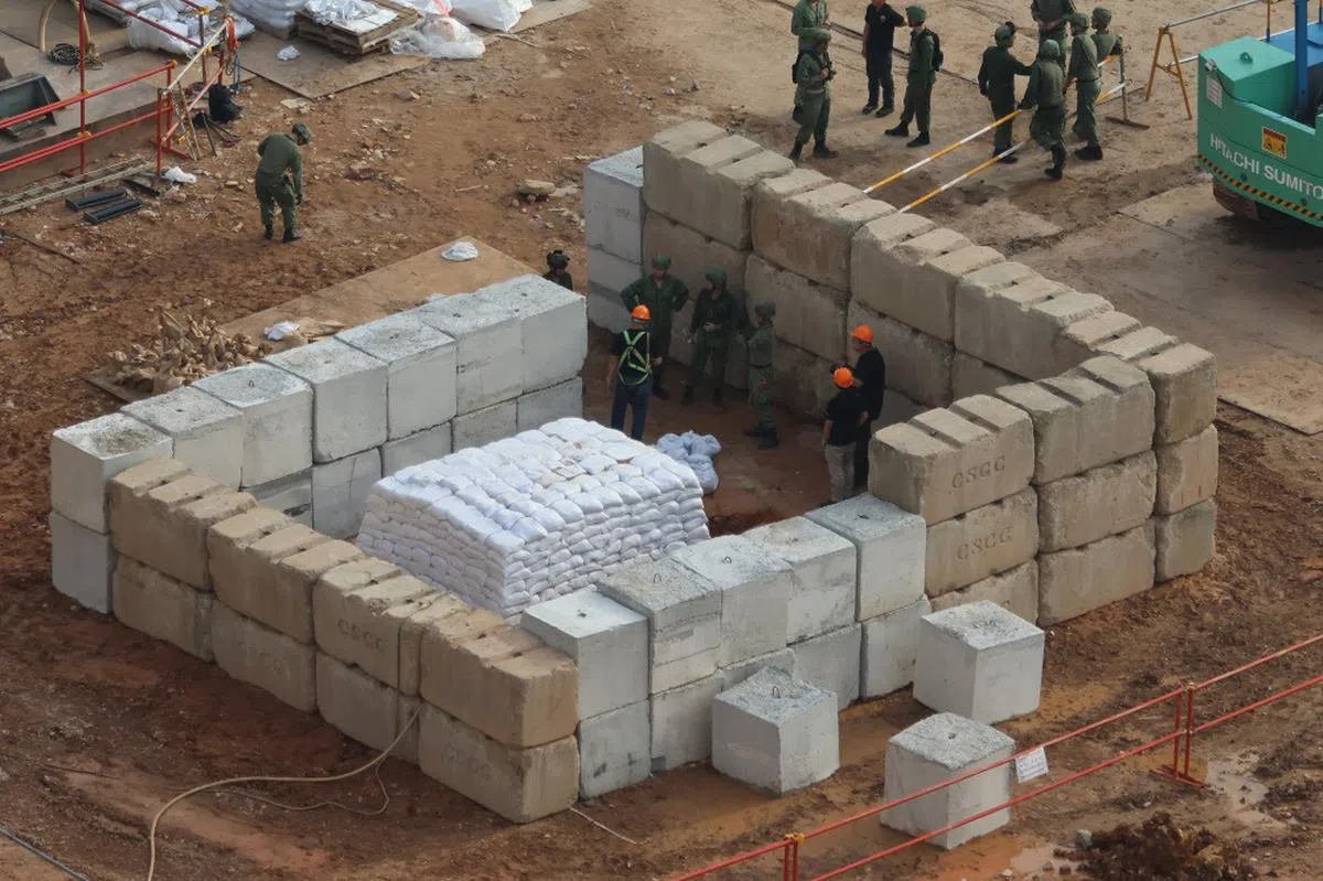 引爆炸弹前，必须先挖掘壕沟，把沙包堆砌在炸弹上方，以及砌起混凝土板作为额外防护。（联合早报）