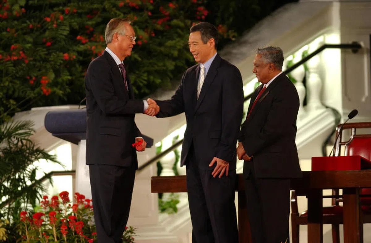  2004年8月12日，李显龙（中）在纳丹总统（右）的见证下，从吴作栋（左）手里接过领导棒子，正式宣誓成为新加坡第三任总理。（海峡时报） 