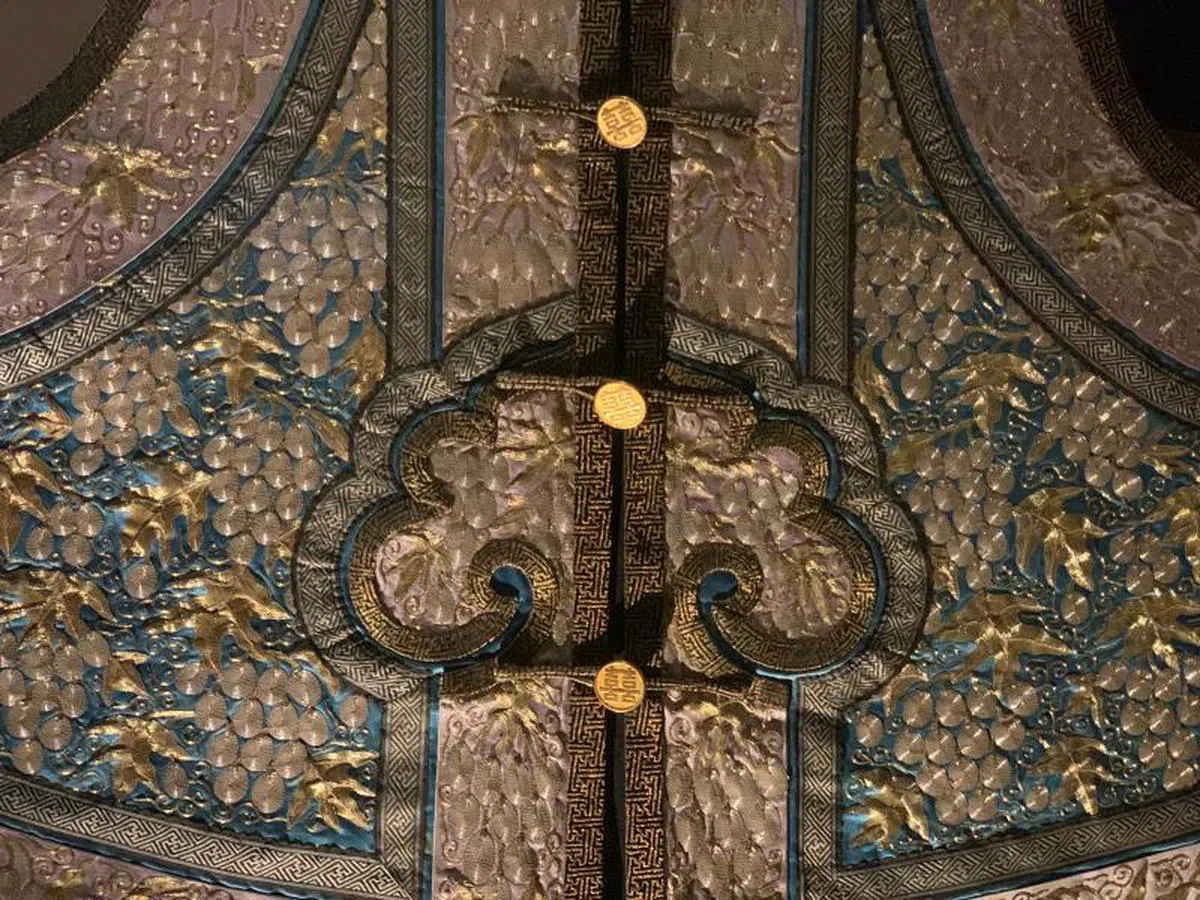  以银丝刺绣而成的葡萄象征丰裕，连纽扣都有双喜字样。（叶孝忠摄） 