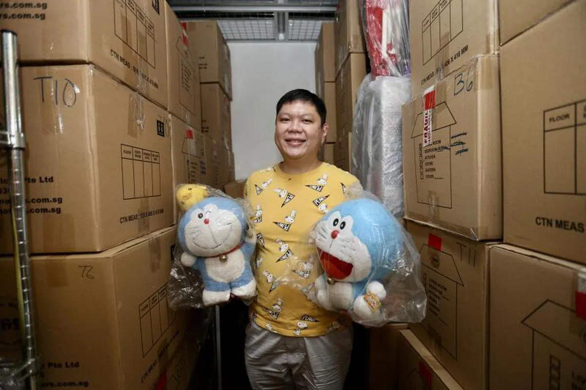 Dave Tay与哆啦A梦公仔，他每周都会定期来到仓库观赏收藏品。（海峡时报）