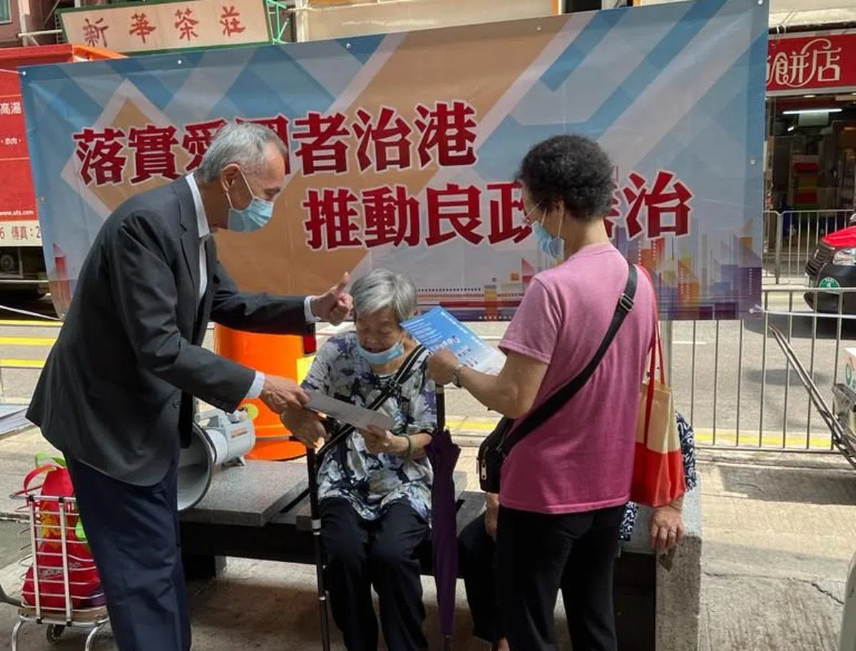 这张2021年的照片显示，作为选委的黄志祥（左）在香港街头与市民交流，宣传香港的新选举制度。（香港商报网）