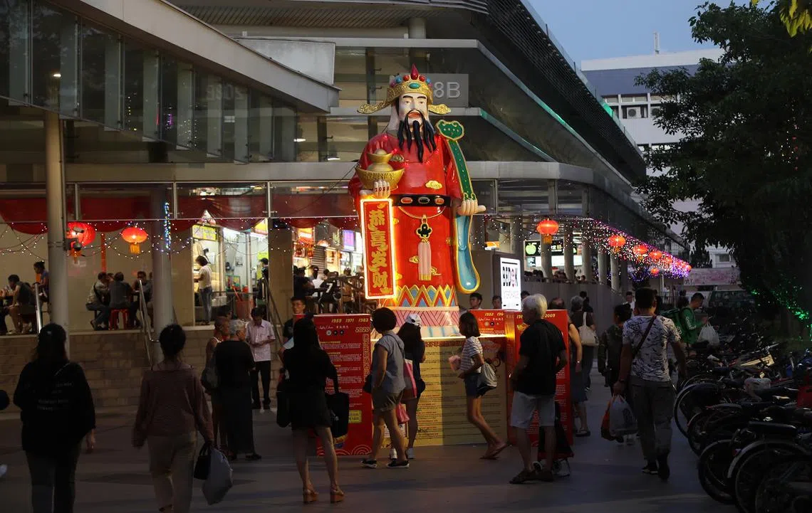 设在勿洛转换站小贩中心前面的财神爷塑像亮起灯来。（联合早报）