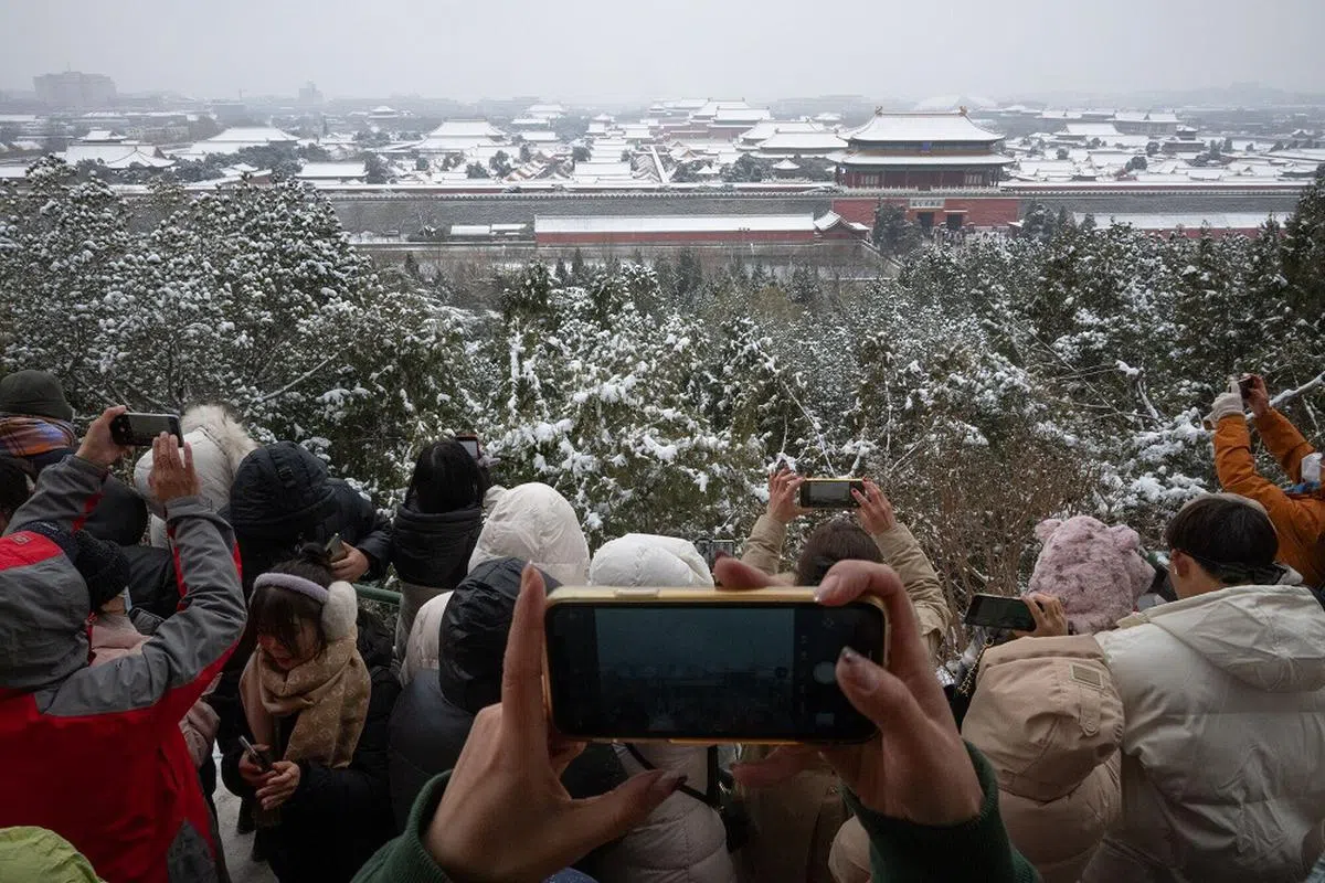 游客们聚集在北京景山上拍摄故宫雪景。（彭博社）
