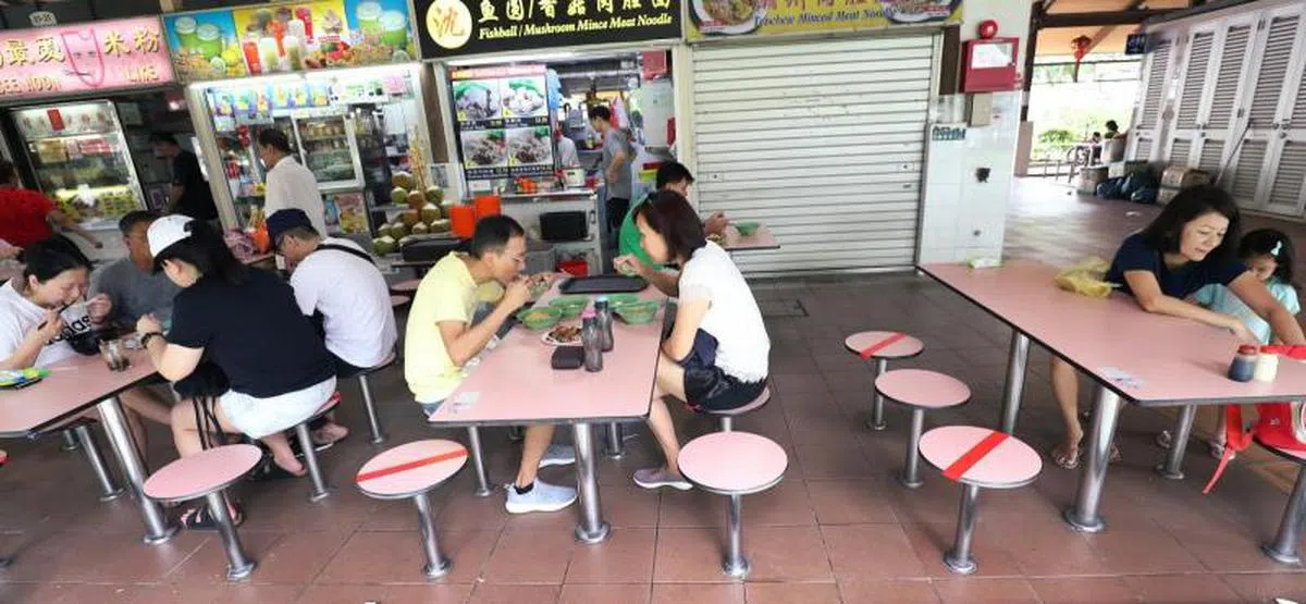  小贩中心的椅子上贴有胶带，提醒人们尽量隔开来用餐，避免病毒传染。（联合早报） 