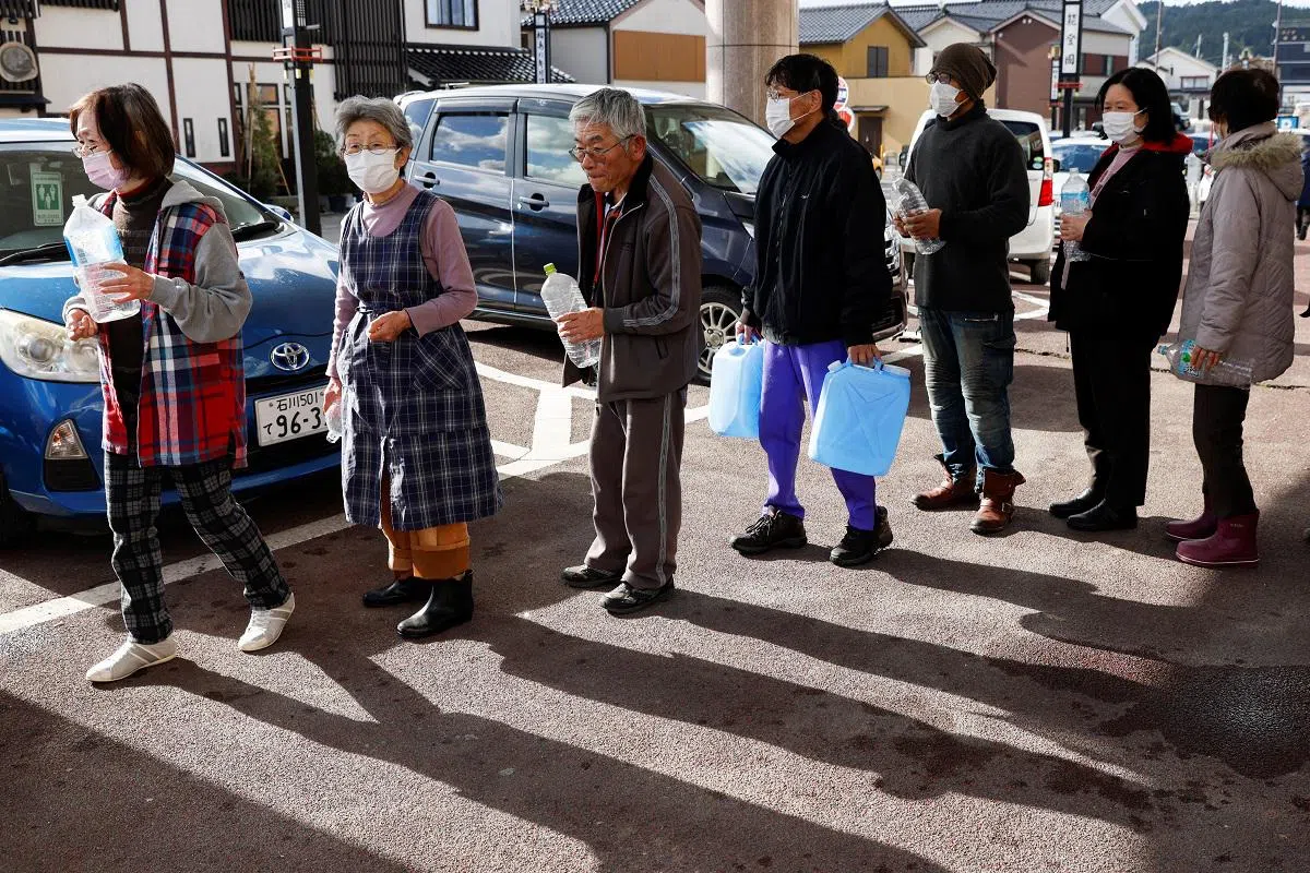 日本地震灾区居民排队取饮用水时，都只取所需的分量，有些人手上的矿泉水空瓶子目测只能装两公升水。（路透社）