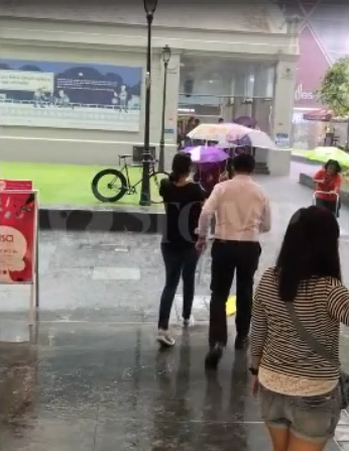  女生把伞倾向陌生人，尽力避免对方被雨淋湿（Stomp视频截图） 