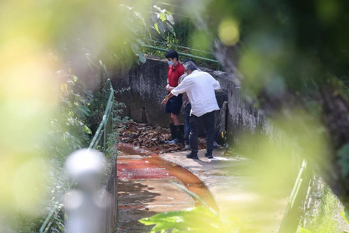 被告叶俊宏（红衣者）承认误杀罪，被判坐牢14年。图为他被警方带回案发现场进行还原案情。（海峡时报）