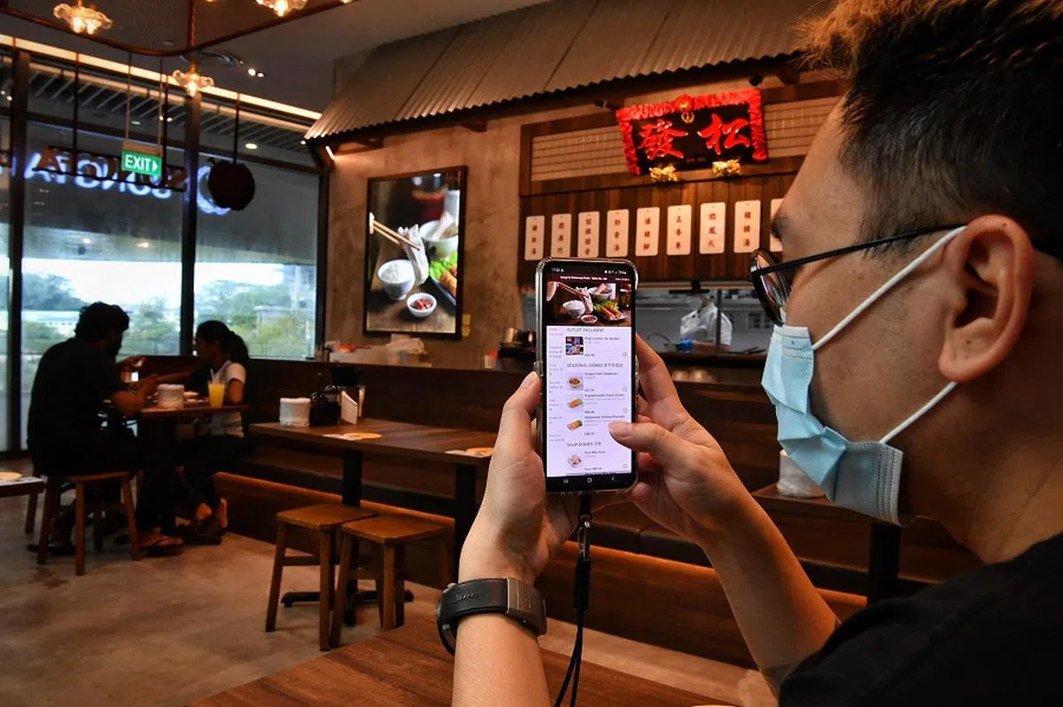 为了节约成本，一些餐饮业者为顾客提供二维码，让他们通过手机扫码点餐。（海峡时报）