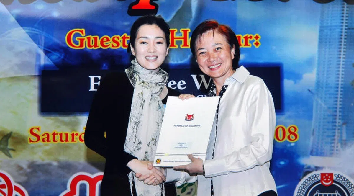  巩俐当年出席新加坡新公民宣誓仪式，从国会议员李美花手中接过公民权证书和粉红色身份证。（联合晚报） 