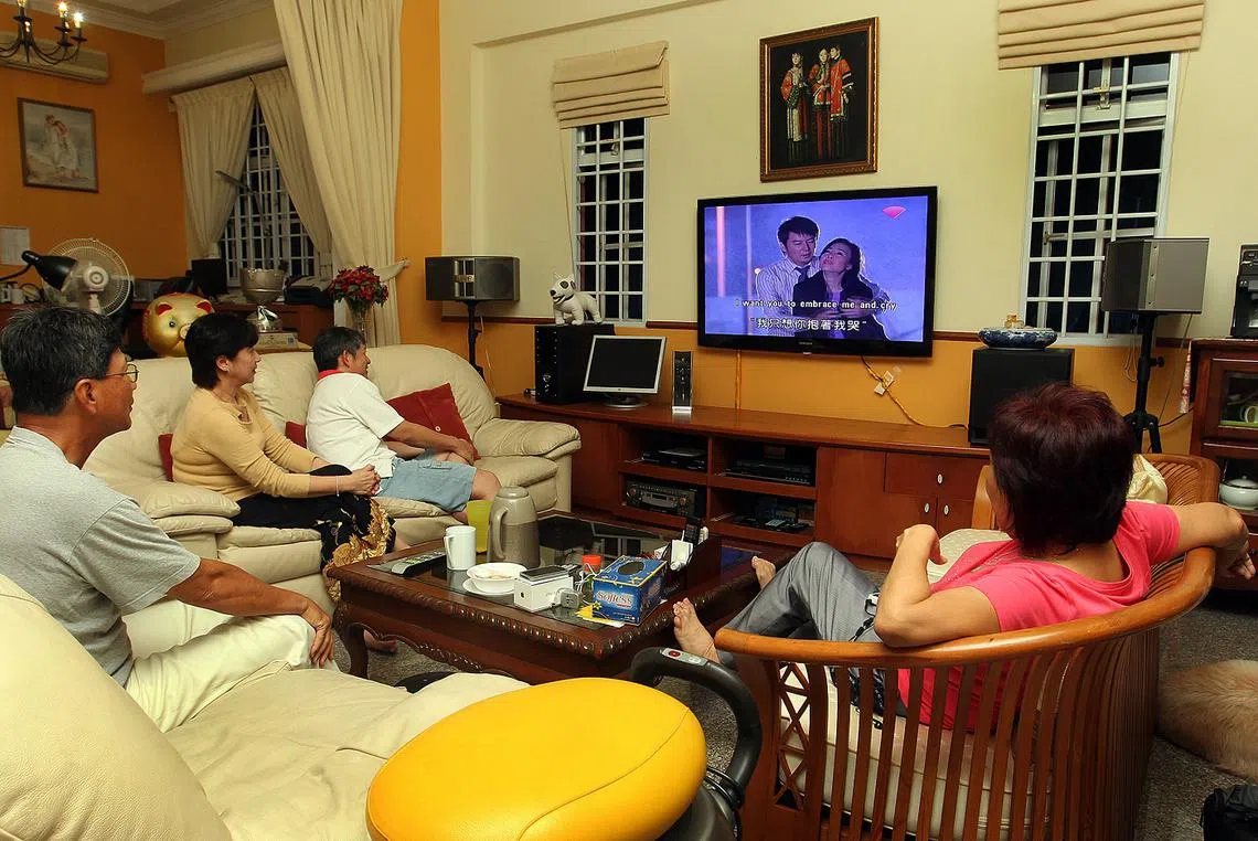 一家人聚在一起看电视。（海峡时报）