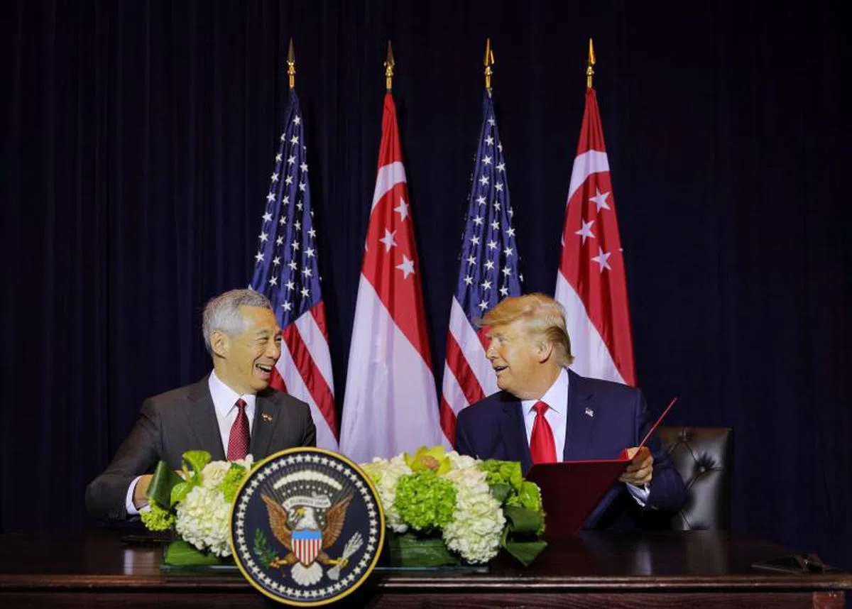 李显龙总理（左）与美国总统特朗普签署文件更新了新美两国1990年防务合作谅解备忘录，允许美国延长使用我国军事设施15年。（海峡时报）