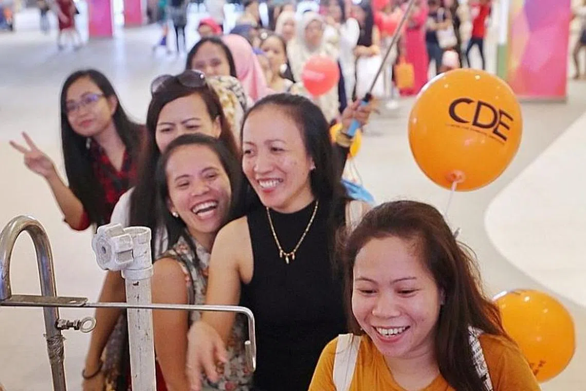 在昨天勿洛心动大厦为家庭佣工举办的活动中，女佣们正在排队领取免费冰淇淋。（海峡时报） 