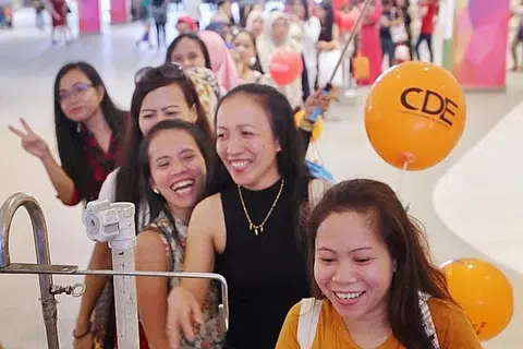 在昨天勿洛心动大厦为家庭佣工举办的活动中，女佣们正在排队领取免费冰淇淋。（海峡时报） 