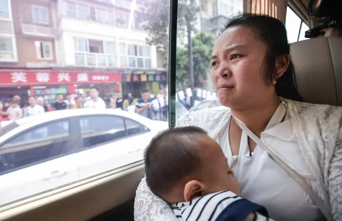  坐在开往父母家的中巴上，康英既期待又忐忑。她的怀里是正在熟睡的小儿子。（新华社） 