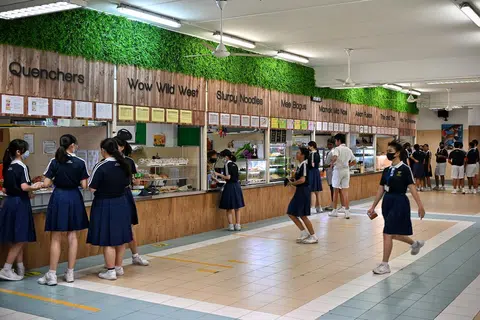  一些现代学校食堂除了装潢和菜式跟过去大不相同，就连摊位的名字都玩起双关语，吸引学生。（海峡时报）