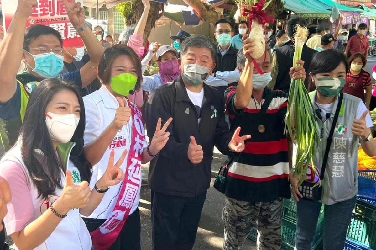 台北市长候选人陈时中（中）的支持者高举蒜苗与其合影。（放言）