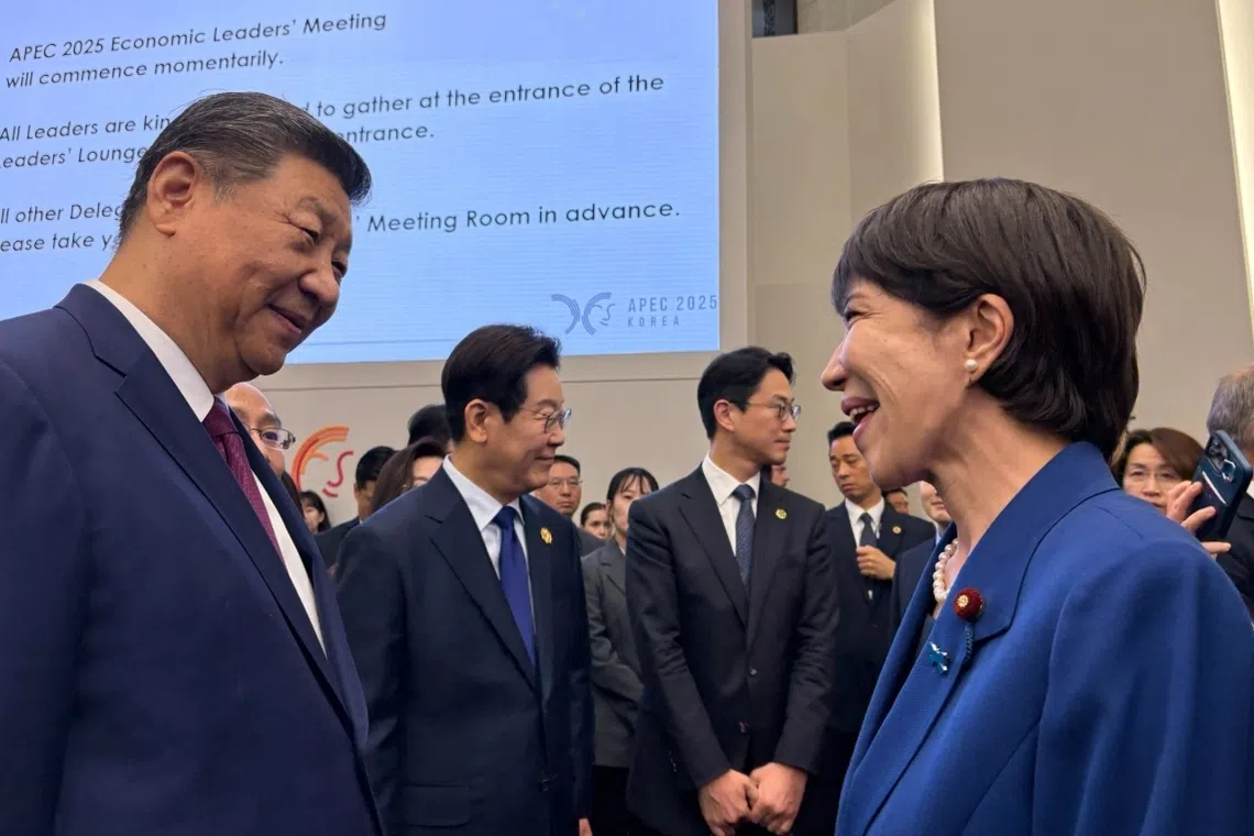 中国国家主席习近平（左一）与日本首相高市早苗（右一）在韩国庆州APEC峰会开始前互致问候，两人脸上都露出笑容，韩国总统李在明（左二）也站在两人旁边。