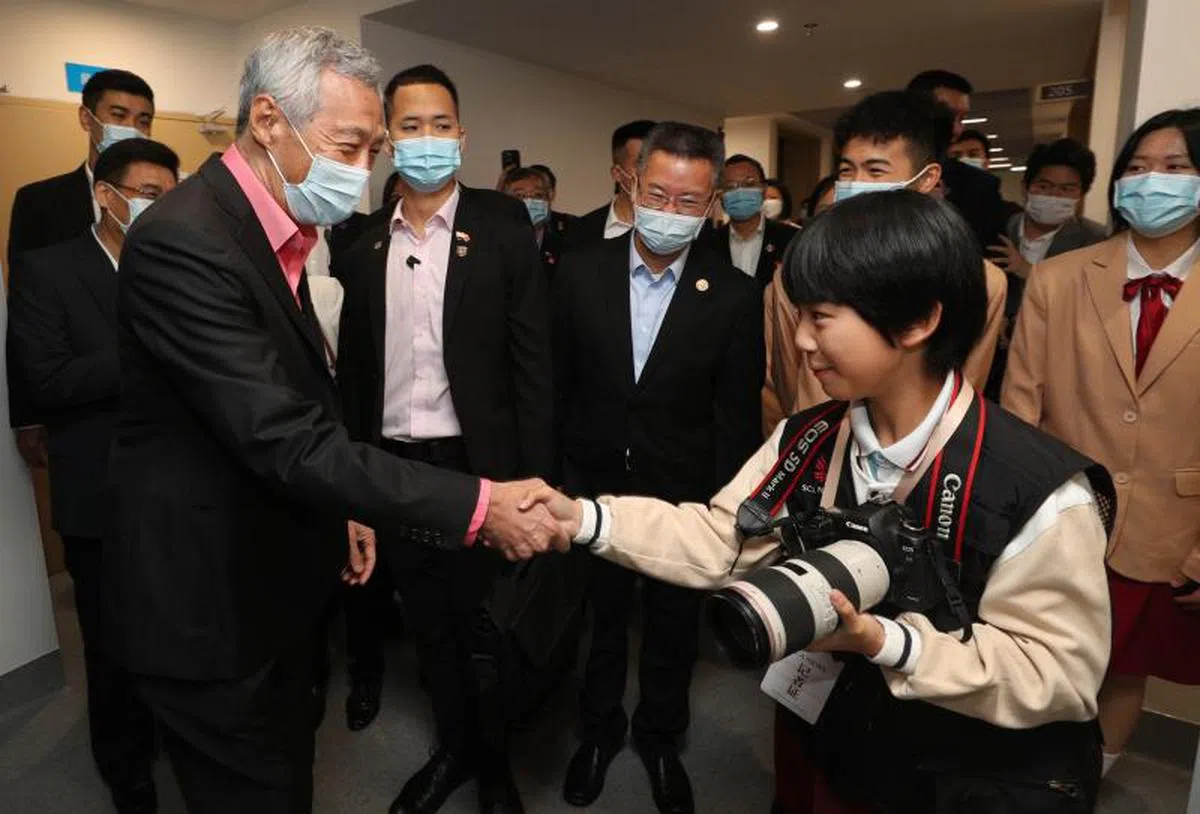 广州新侨学校有校园记者的课外活动，李显龙总理访问校园期间，有很多校园记者随同拍摄记录。与李总理握手的是来自该校六年级的学生Jerry Wang。（新加坡通讯及新闻部提供）