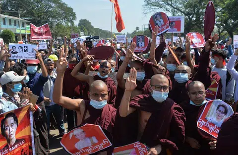 缅甸首都内比都，僧侣在2021年2月13日举着印有国防军总司令敏昂莱样貌的海报抗议。（法新社）